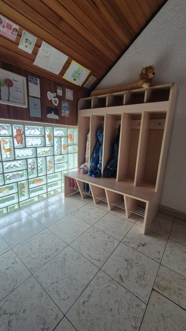 Ein Umkleidebereich mit Holzschränken und einer Glaswand, auf dem Boden Schuhe abgelegt.